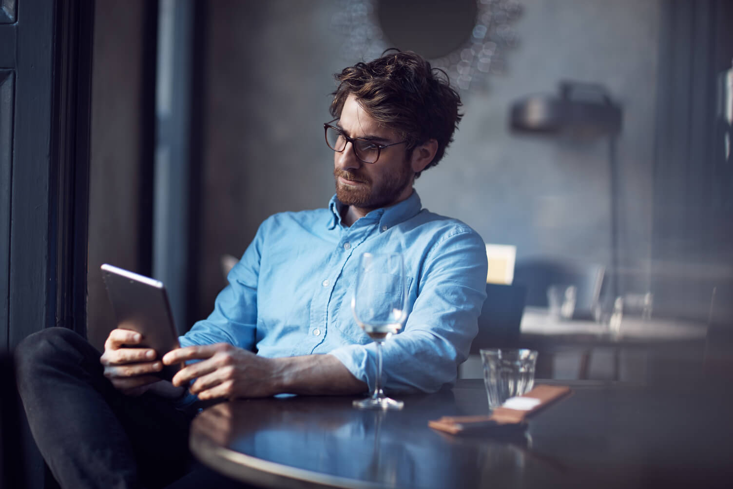 man in a blue shirt sat down looking at a tablet