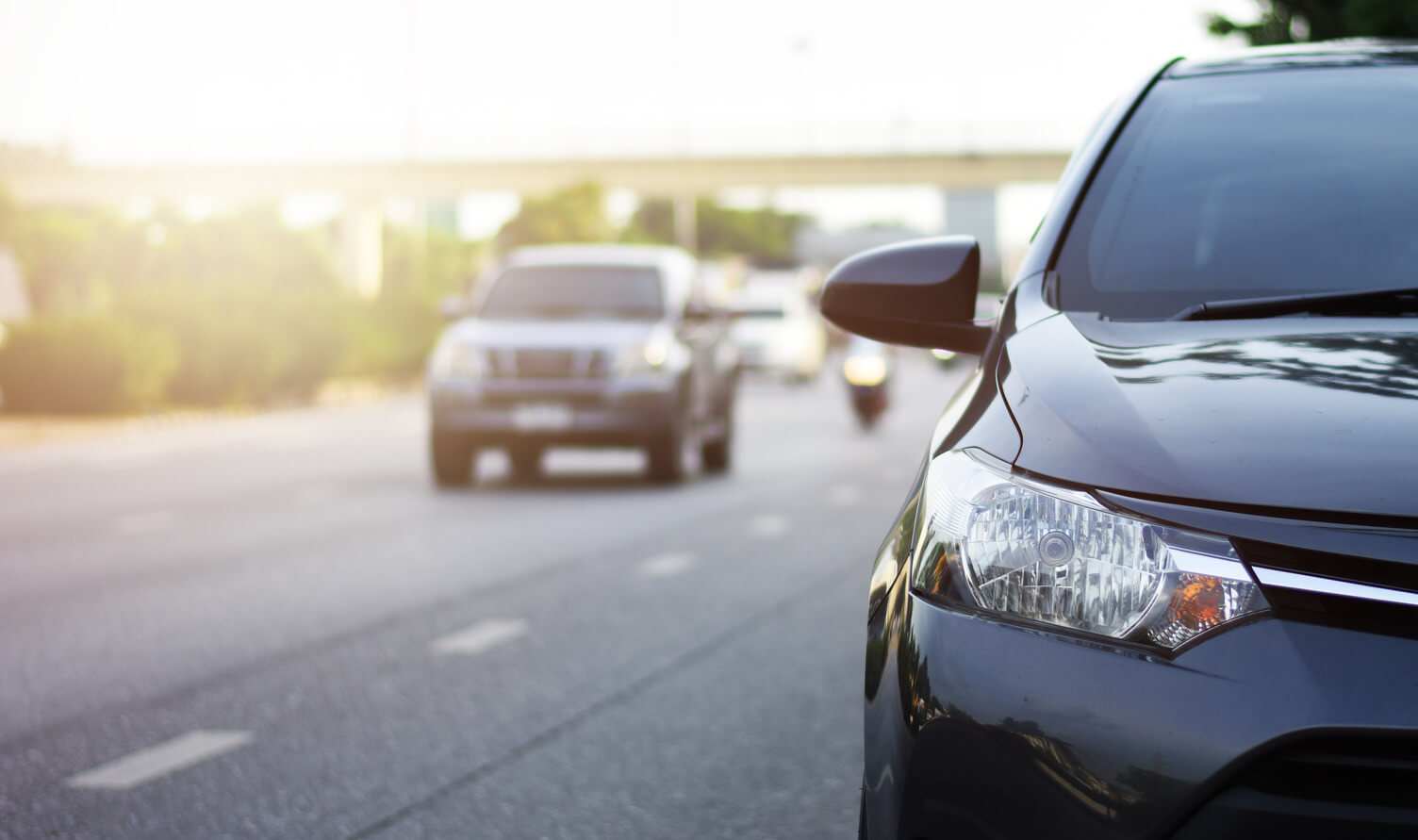 a front facing image of a black car driving down a motorway