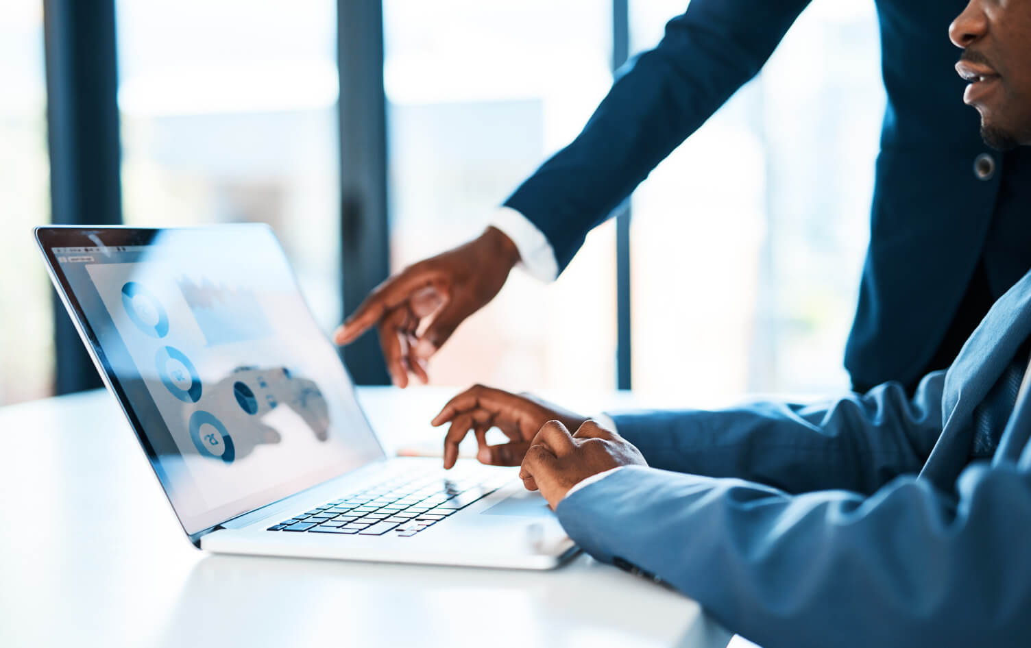 two people looking at data on a laptop, one is pointing at the screen